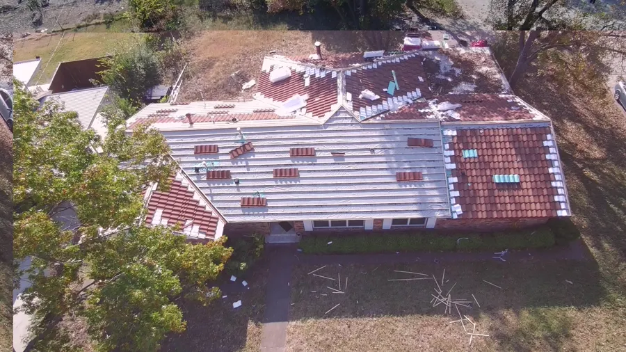 Aerial view of a tile roof being laid over new white underlayment, tiles stacked in rows