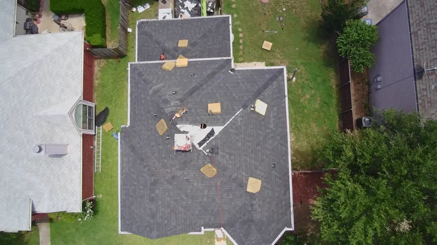 Top-down drone view of a completed architectural shingle roof with the last bundles on deck