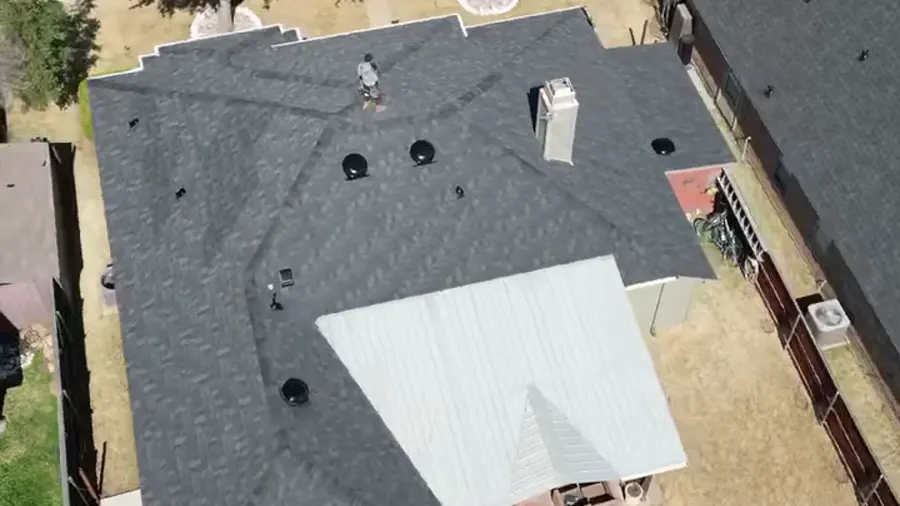 Drone view of a finished shingle roof and patio cover from above the backyard