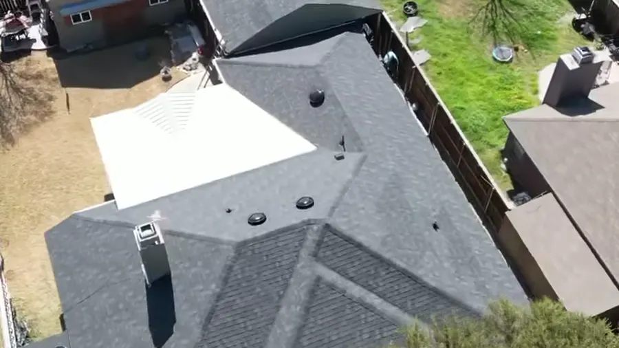 Drone view of a finished shingle roof from above the front lawn